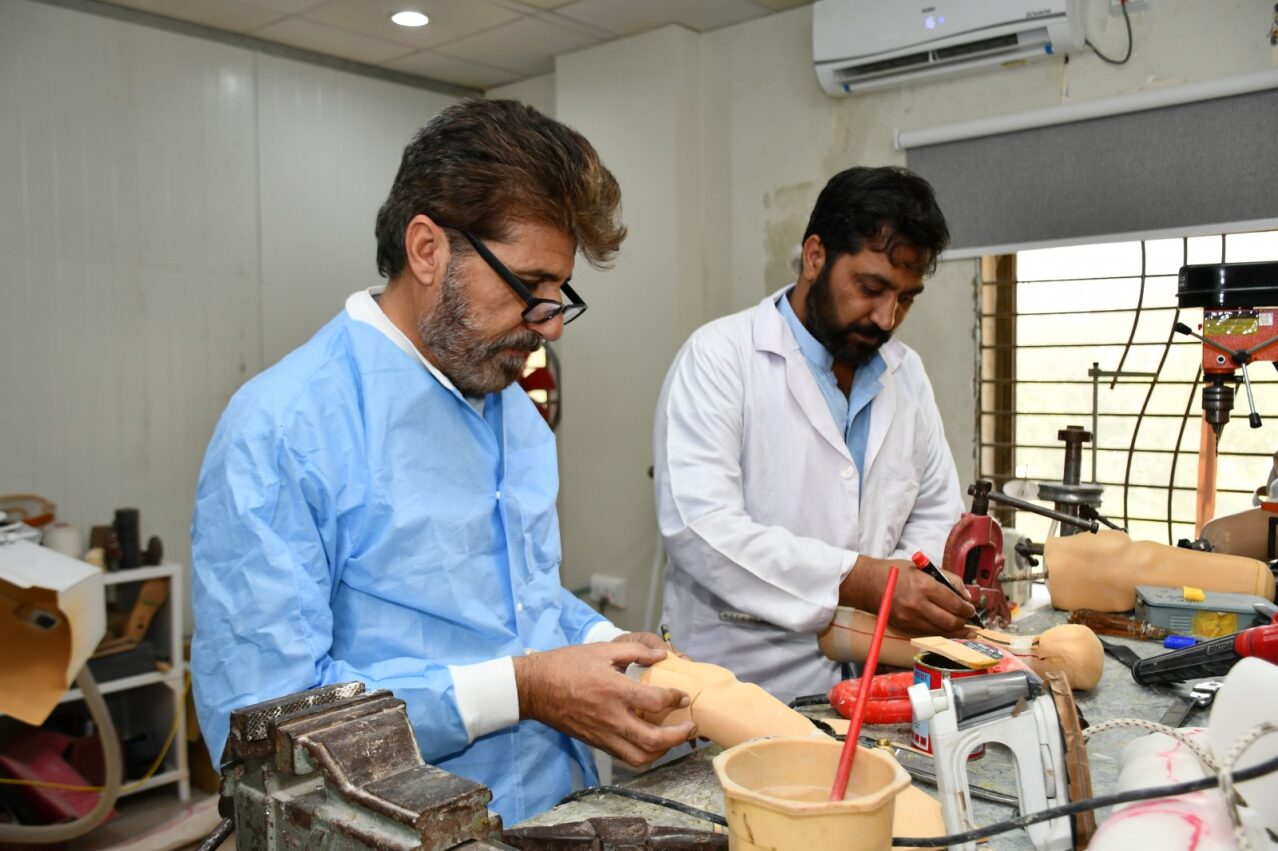 HHRD prosthetists shaping and finishing custom prosthetic limbs in the on-site workshop